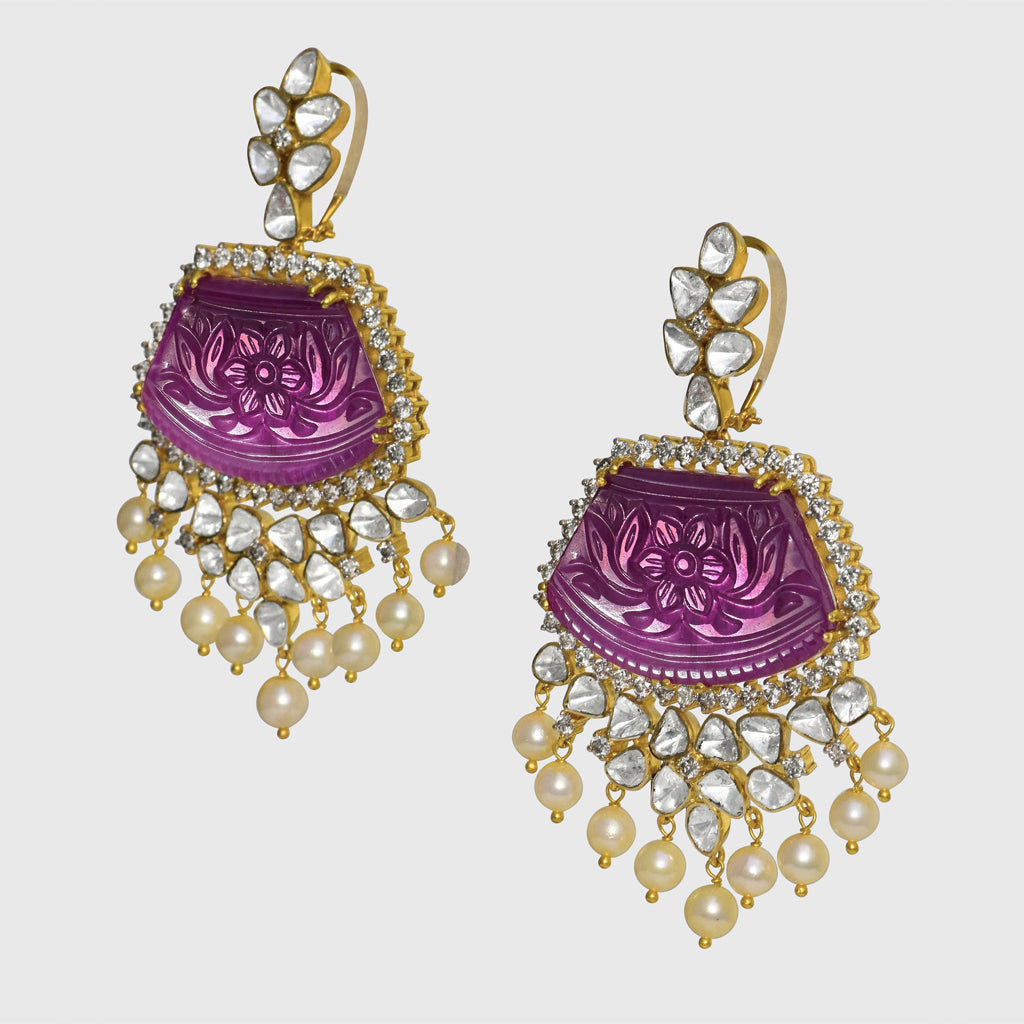 our luxurious long earrings adorned with intricately carved ruby stones, shimmering diamond polki, and radiant diamond rounds. Complete with delicate pearl hangings, these earrings exude timeless sophistication and charm. (GDE0437)